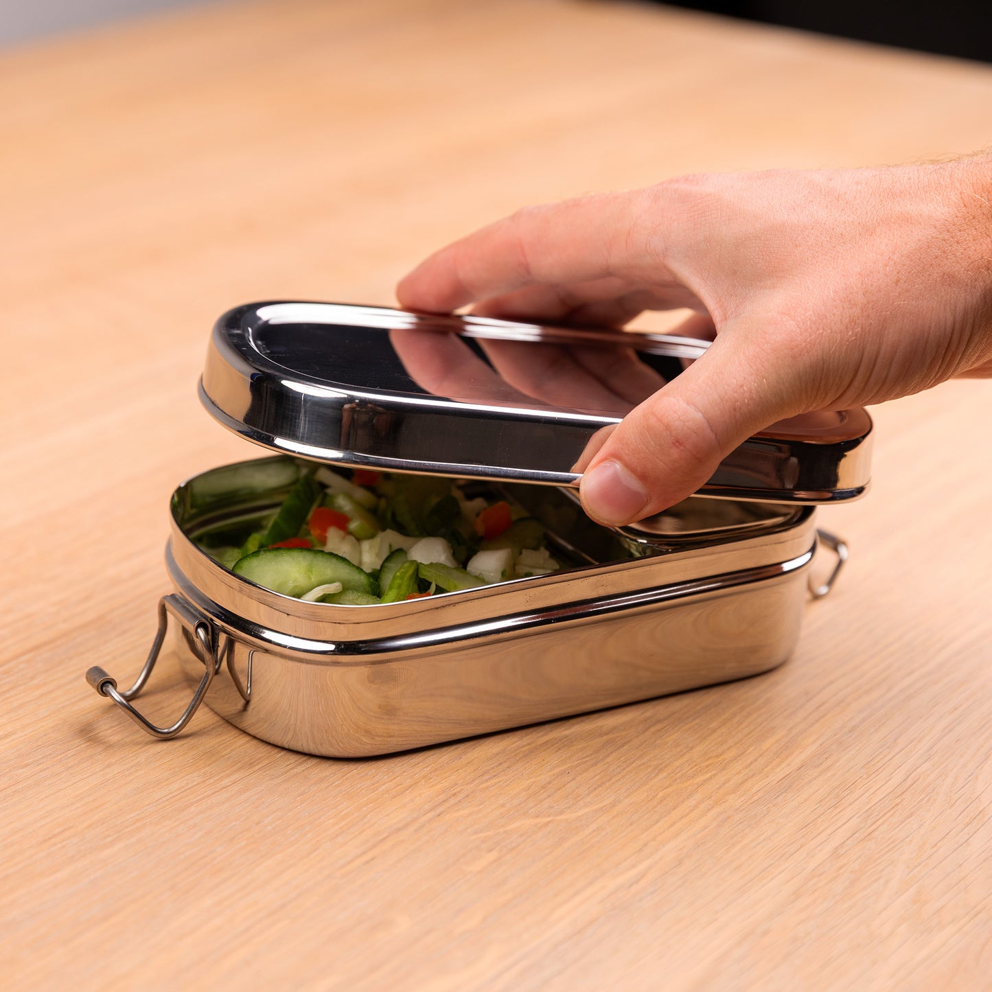 RVS lunchbox met vakjes die wordt geopend door een hand