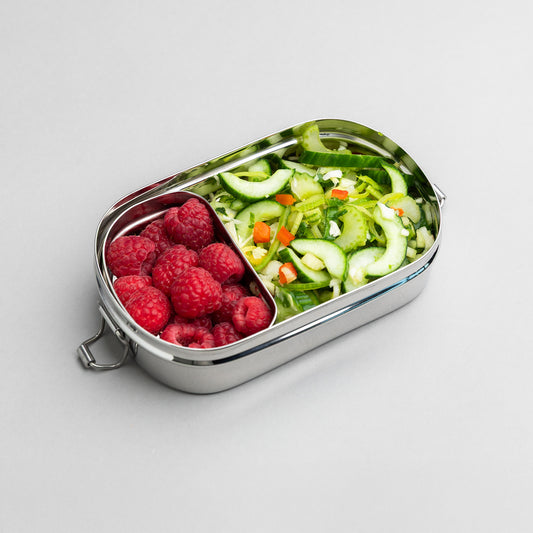 RVS lunchbox met vakjes gevuld met framboos en salade