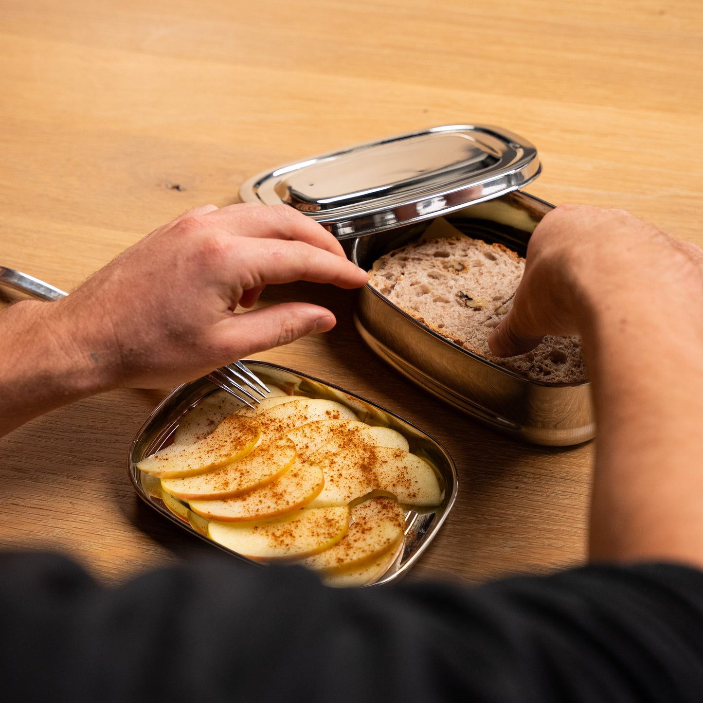 Rvs Lunchbox met vakjes. een hand pakt een boterham uit de broodtrommel