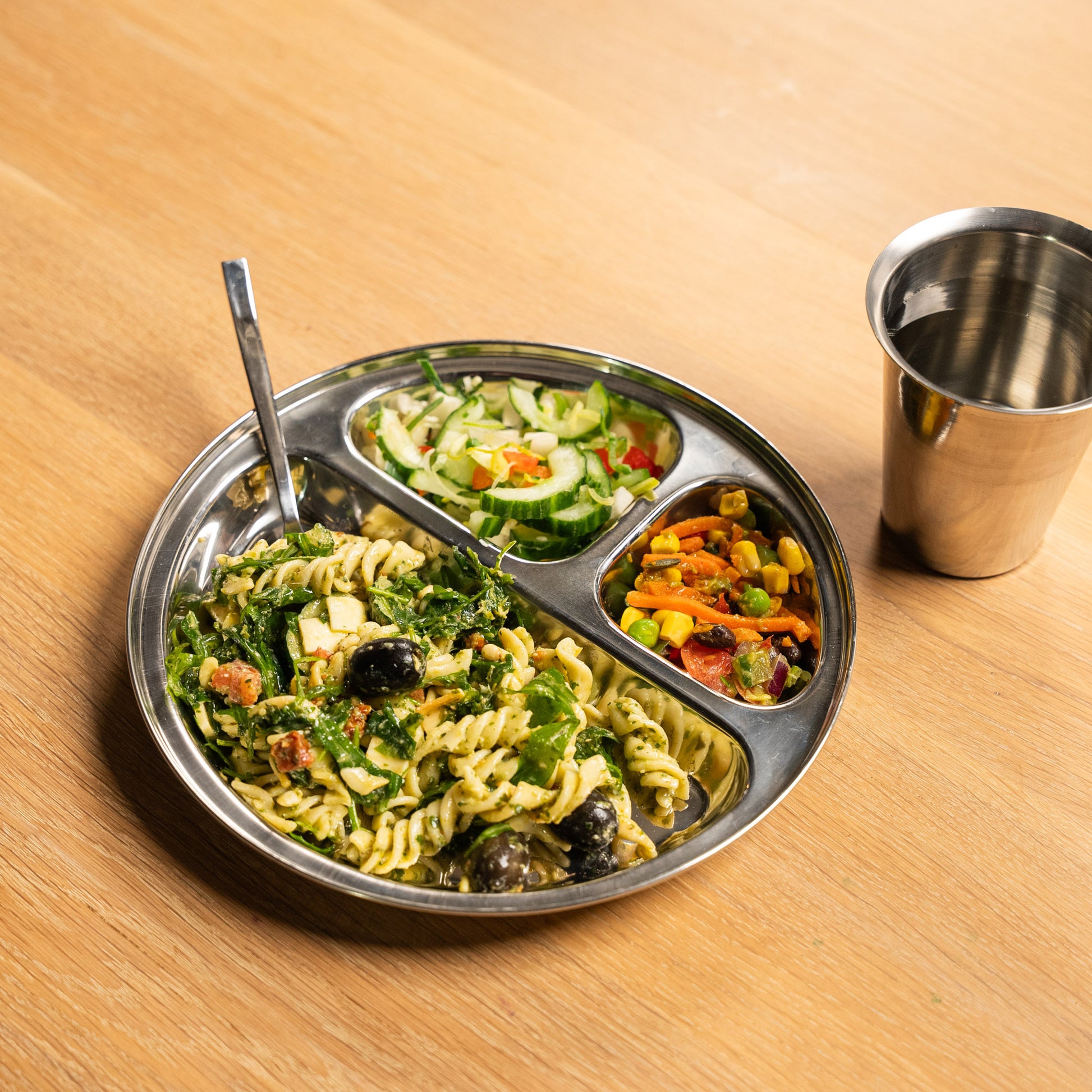 RVS bord met vakjes uit India op een tafel met lepel en een glas