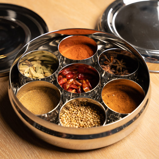 RVS Masala dabba, spice box gevuld met specerijen op een houten tafel