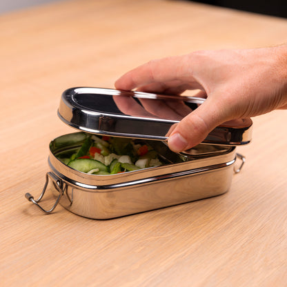 RVS lunchbox met vakjes die wordt geopend door een hand